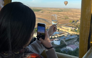 passenger taking pictures of hot air balloon while toasting with champagne